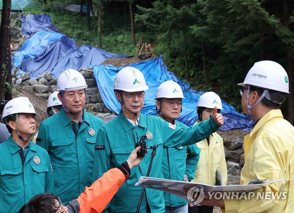 El primer ministro Han Duck-soo (centro) y el alcalde de Seúl, Oh Se-hoon (segundo desde la izquierda), visitan un área en Seocho Ward, Seúl, el 23 de julio de 2023, para inspeccionar los esfuerzos de recuperación del deslizamiento de tierra del año pasado y los preparativos para un posible deslizamiento de tierra, ya que las lluvias torrenciales han azotado al país desde principios de este mes.  (Yonhap)
