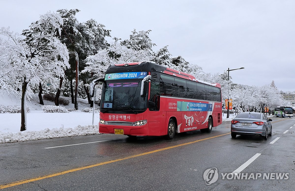 Un autobús lanzadera para los Juegos Olímpicos de la Juventud de Invierno viaja por una carretera en Gangneung, provincia de Gangwon, despejada de nieve el 21 de enero de 2024, después de las fuertes nevadas de la noche a la mañana.  (Yonhap)