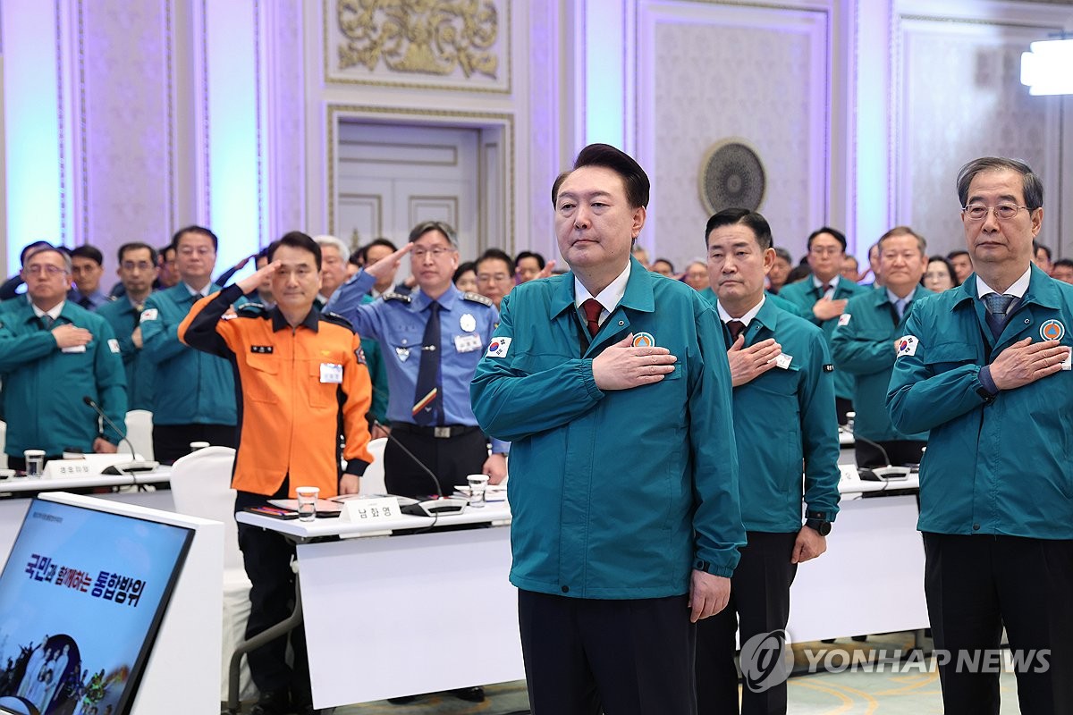 President Yoon Suk Yeol (front) salutes the national flag during a meeting on integrated defense at Cheong Wa Dae, the former presidential office, in Seoul on Jan. 31, 2024. The meeting is aimed at discussing ways to ensure unity among the administrative, military and police branches, as well as civilians, in the country's defense. (Yonhap)