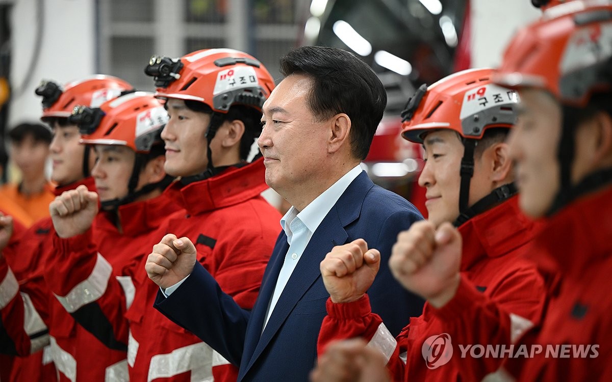 Esta foto, proporcionada por la oficina presidencial el 15 de septiembre de 2024, muestra al presidente Yoon Suk Yeol (tercero desde la derecha) posando para una foto con los bomberos de servicio durante las vacaciones de la cosecha de otoño de Chuseok durante su visita a la estación de bomberos de Gangseo en Seúl. (FOTO NO A LA VENTA) (Yonhap)