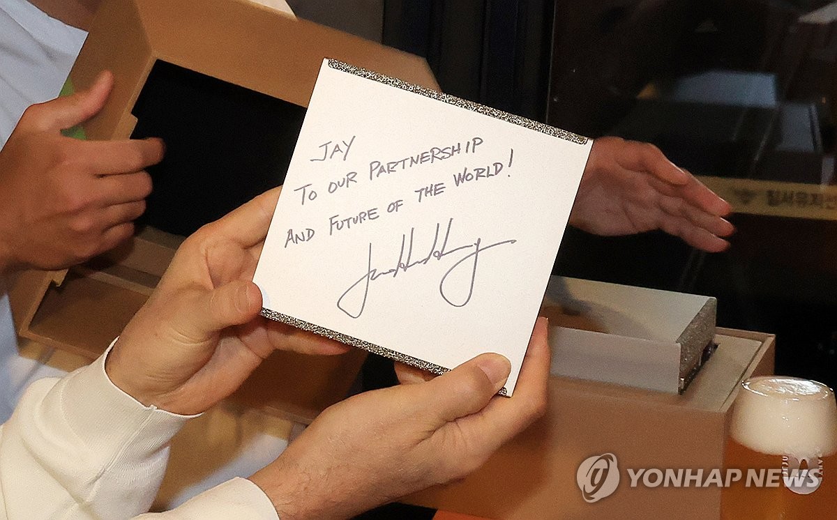 Samsung Electronics Chairman Lee Jae-yong holds a card presented by Nvidia Chief Executive Officer Jensen Huang at a restaurant in Seoul on Oct. 30, 2025. (Pool photo) (Yonhap)